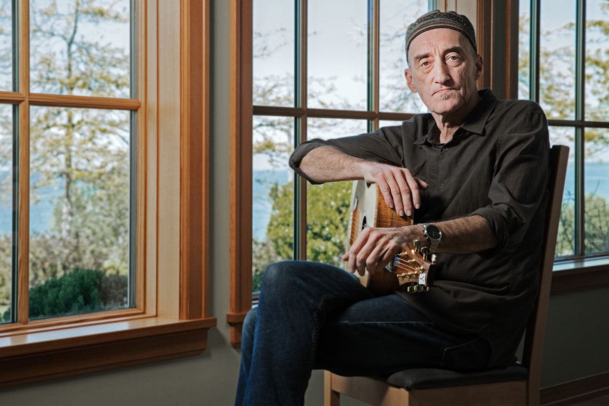 Miroslav Tadić testing a custom acoustic guitar with figured koa back and sides and a light-coloured spruce top.