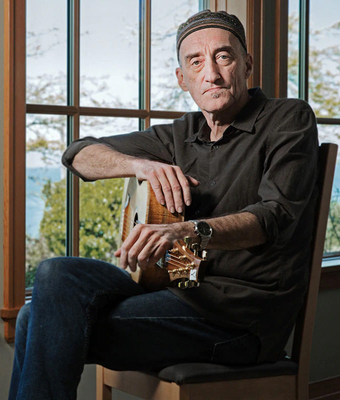 Miroslav Tadić testing a custom acoustic guitar with figured koa back and sides and a light-coloured spruce top.