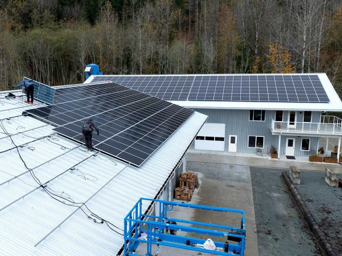 Workers installing solar panels on the roof of Pacific Rim Tonewoods' facility, advancing sustainability efforts.