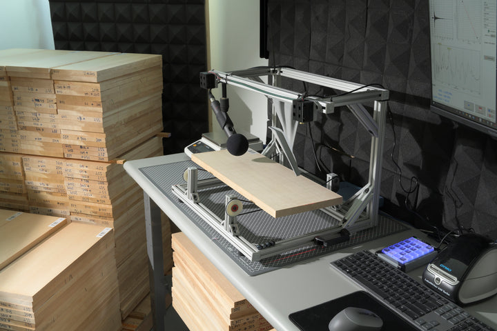 BING sonic grading system analyzing a tonewood sample at Pacific Rim Tonewoods, with spectral data shown on screen and stacks of labeled wood nearby