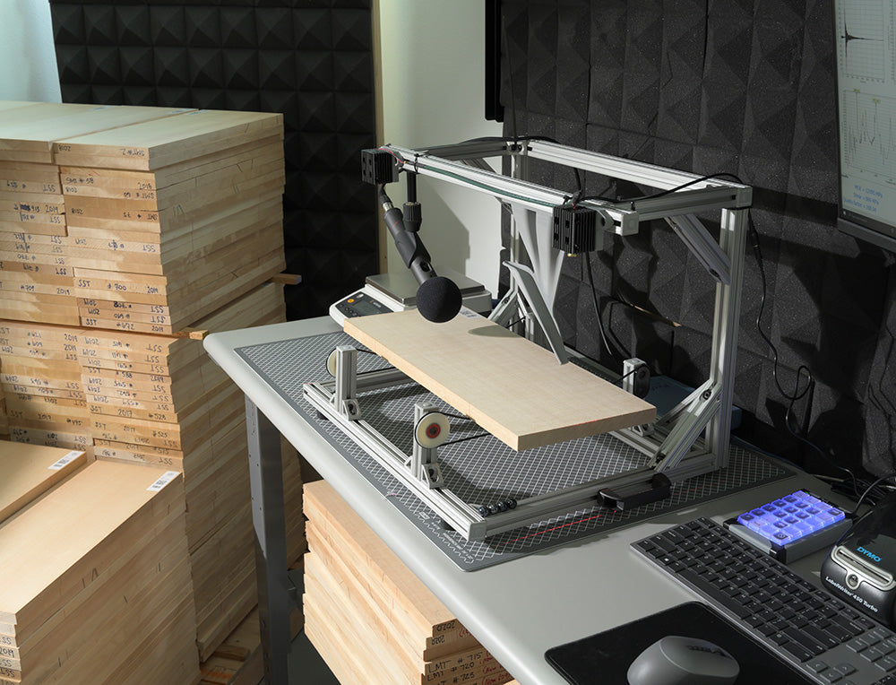 BING sonic grading system analyzing a tonewood sample at Pacific Rim Tonewoods, with spectral data shown on screen and stacks of labeled wood nearby.