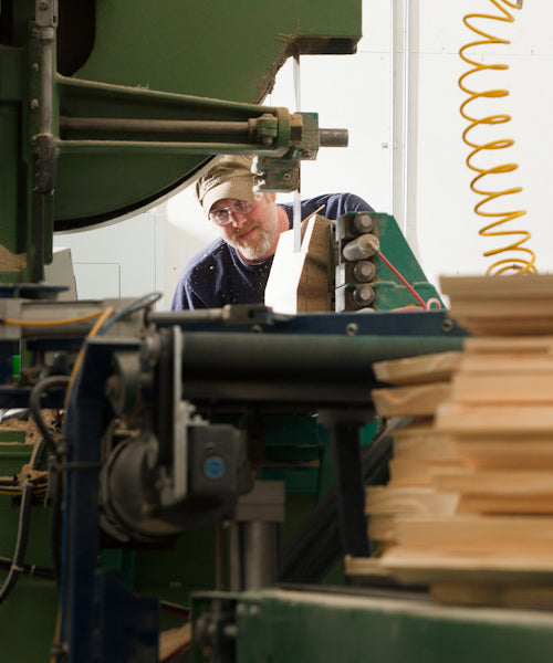 A man works on a piece of wood in a Pacific Rim tonewood workshop.