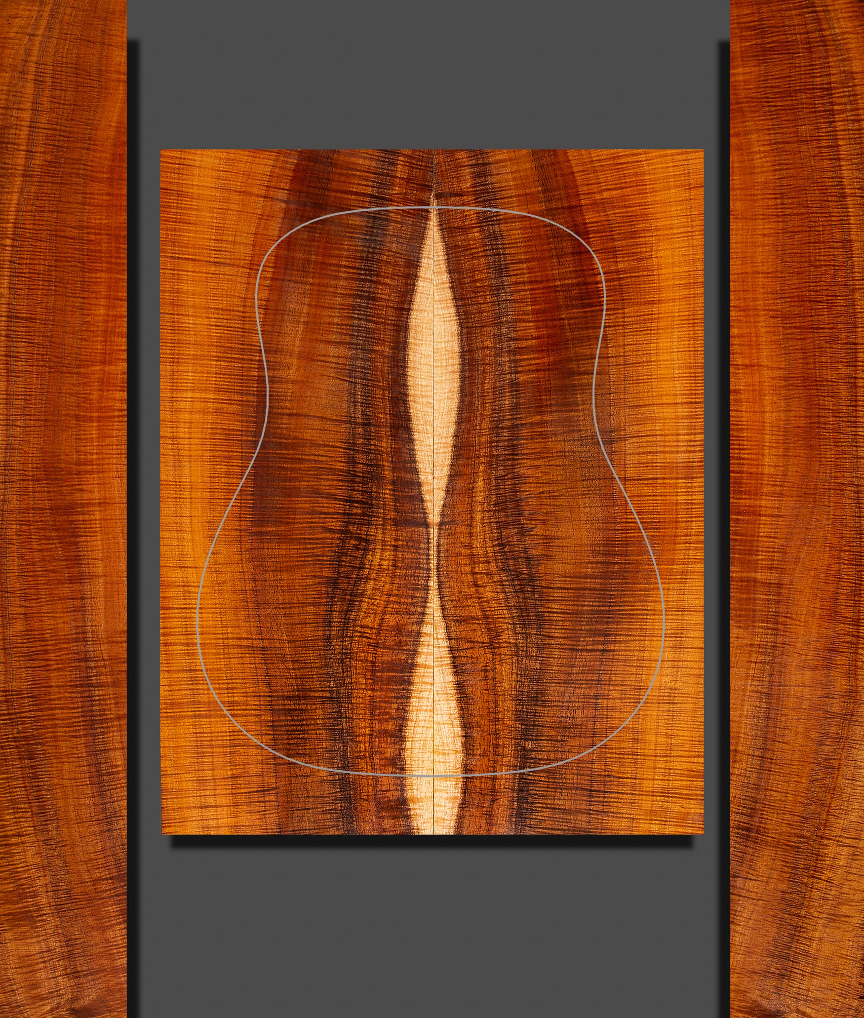 Striking koa back and side set for acoustic guitar with vivid sapwood center and bold, curly figure. White outline marks guitar body shape.