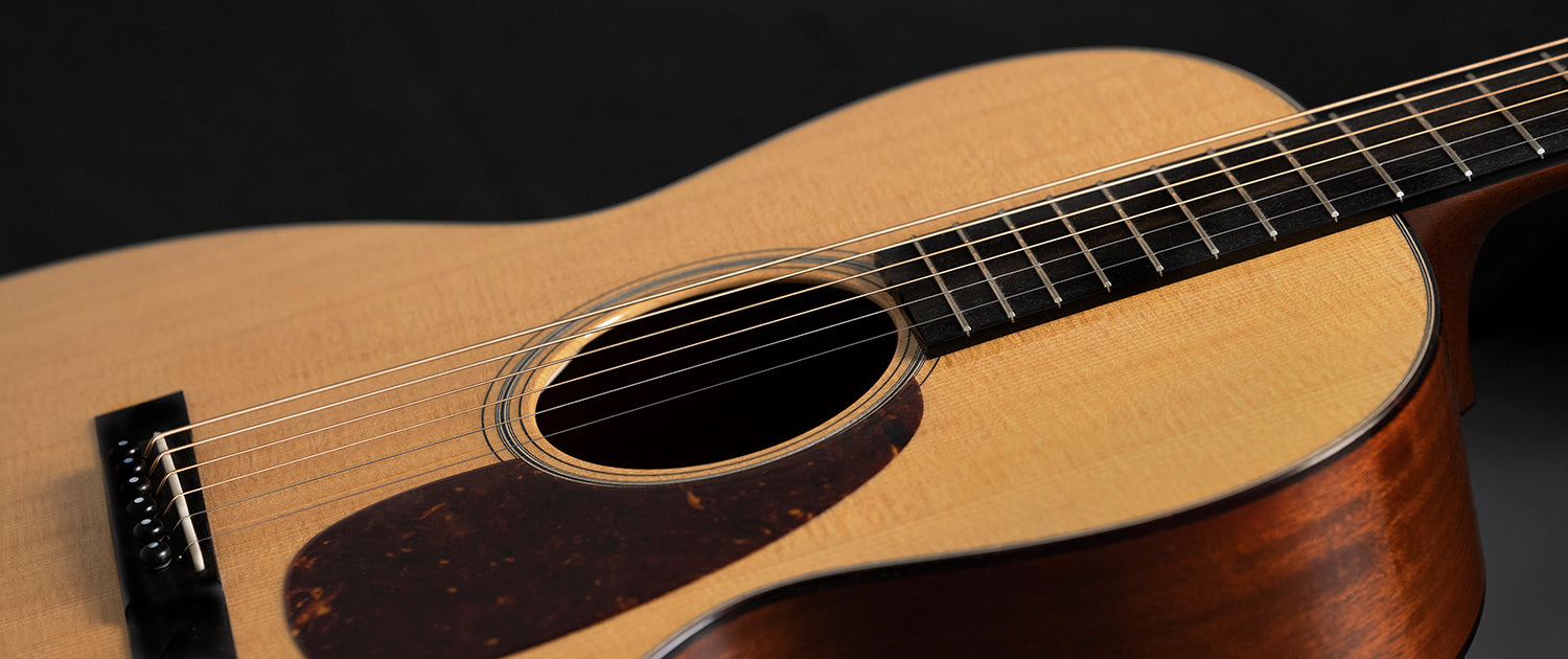 A close-up of a torrefied acoustic guitar top showing rich wood grain and warm, golden tones.